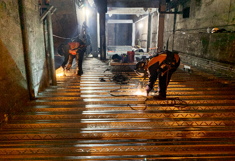 To house powerful new tunnel ventilation fans, a “second floor” was built over the tracks. Two massive steel bridges were built across both tunnels. Here, the steel decking is being welded in place to support a concrete floor.