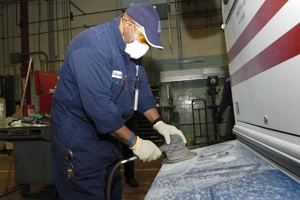 A Metro employee works on the body of a Metrobus.
