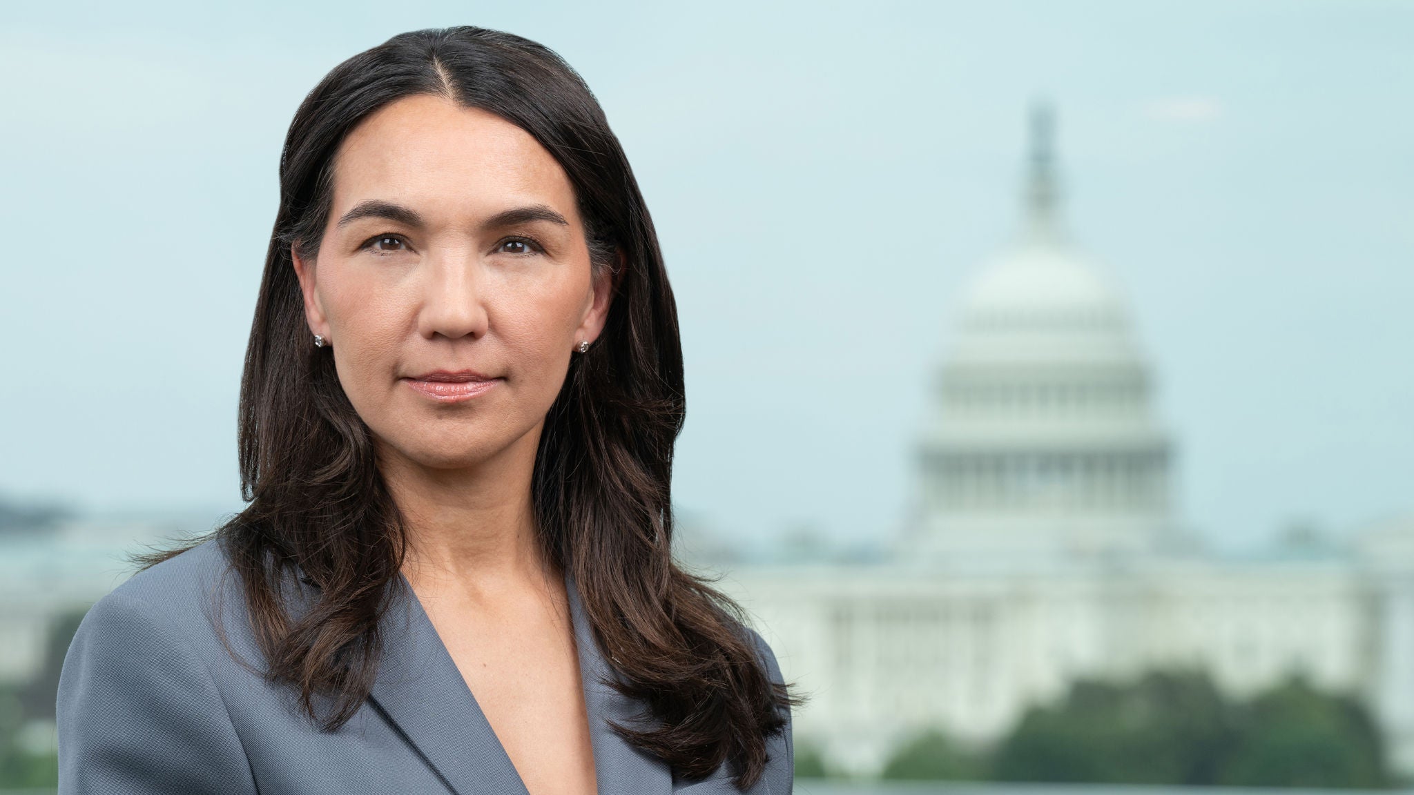 Headshot of Director Valerie Santos in a grey suit.