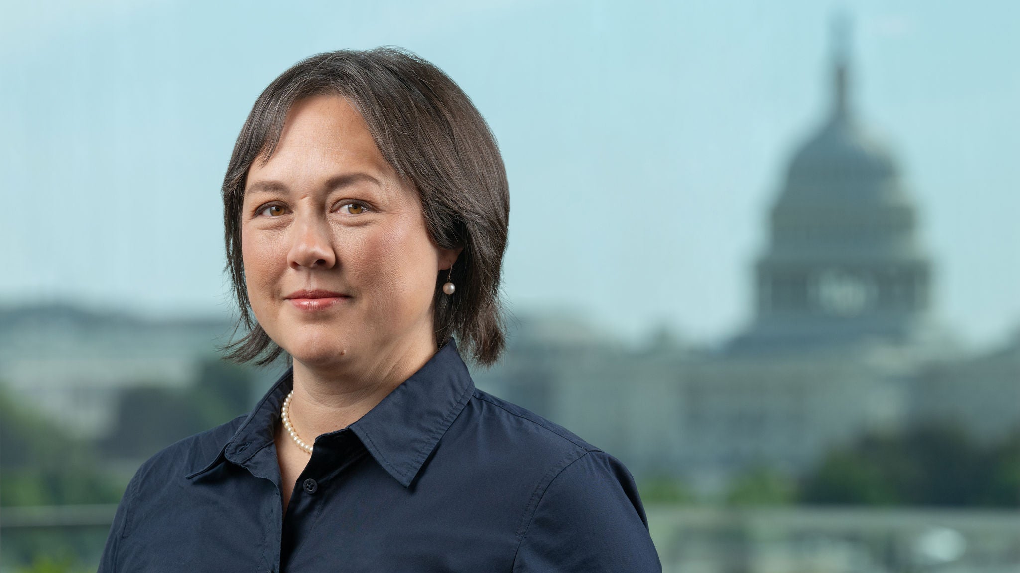 Headshot of Director Tracy Hadden Loh in a black collared shirt.