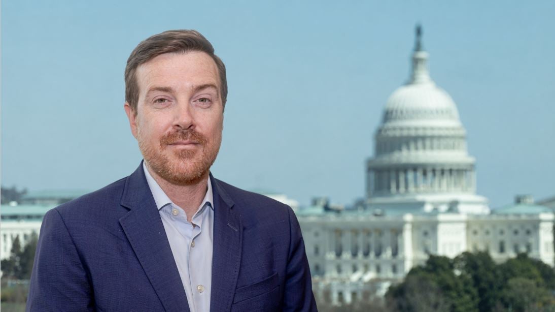 Headshot of Director Joe McAndrew in a navy suit.