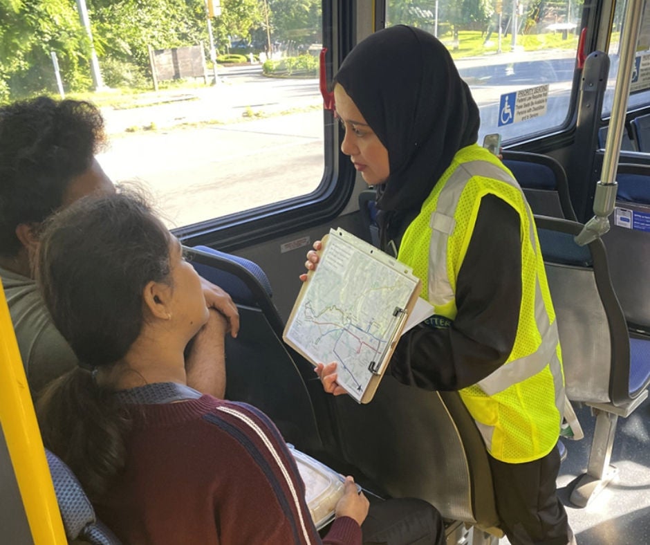 Larawan ng babae na nagpapakita ng mga tao sa mga mapa ng ruta ng bus