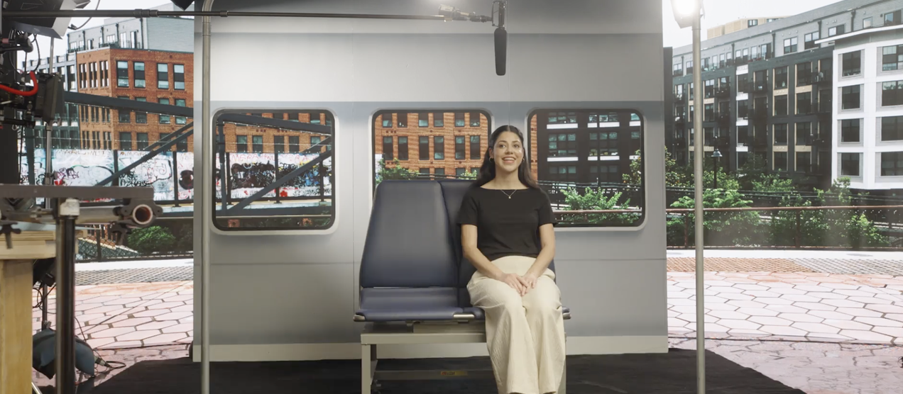 Ashley sitting on a replica of a metro rail seat
