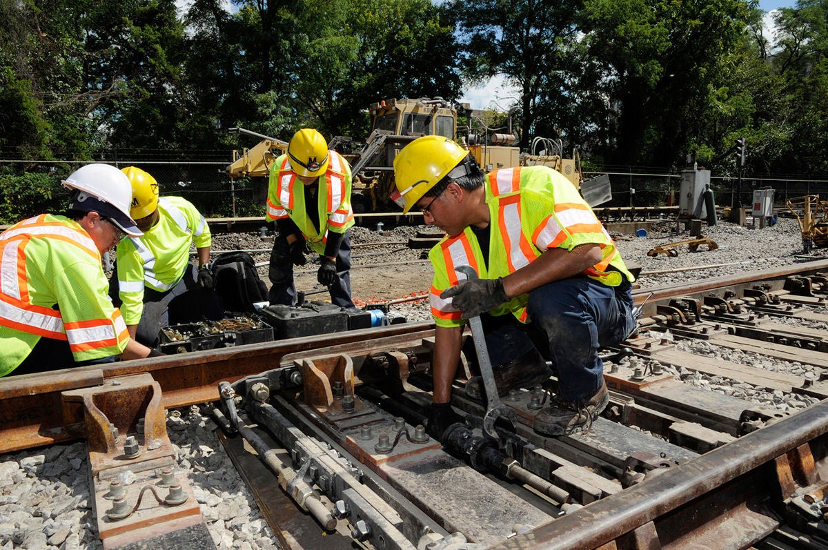 4 construction workers conducting track work on Metro Rail