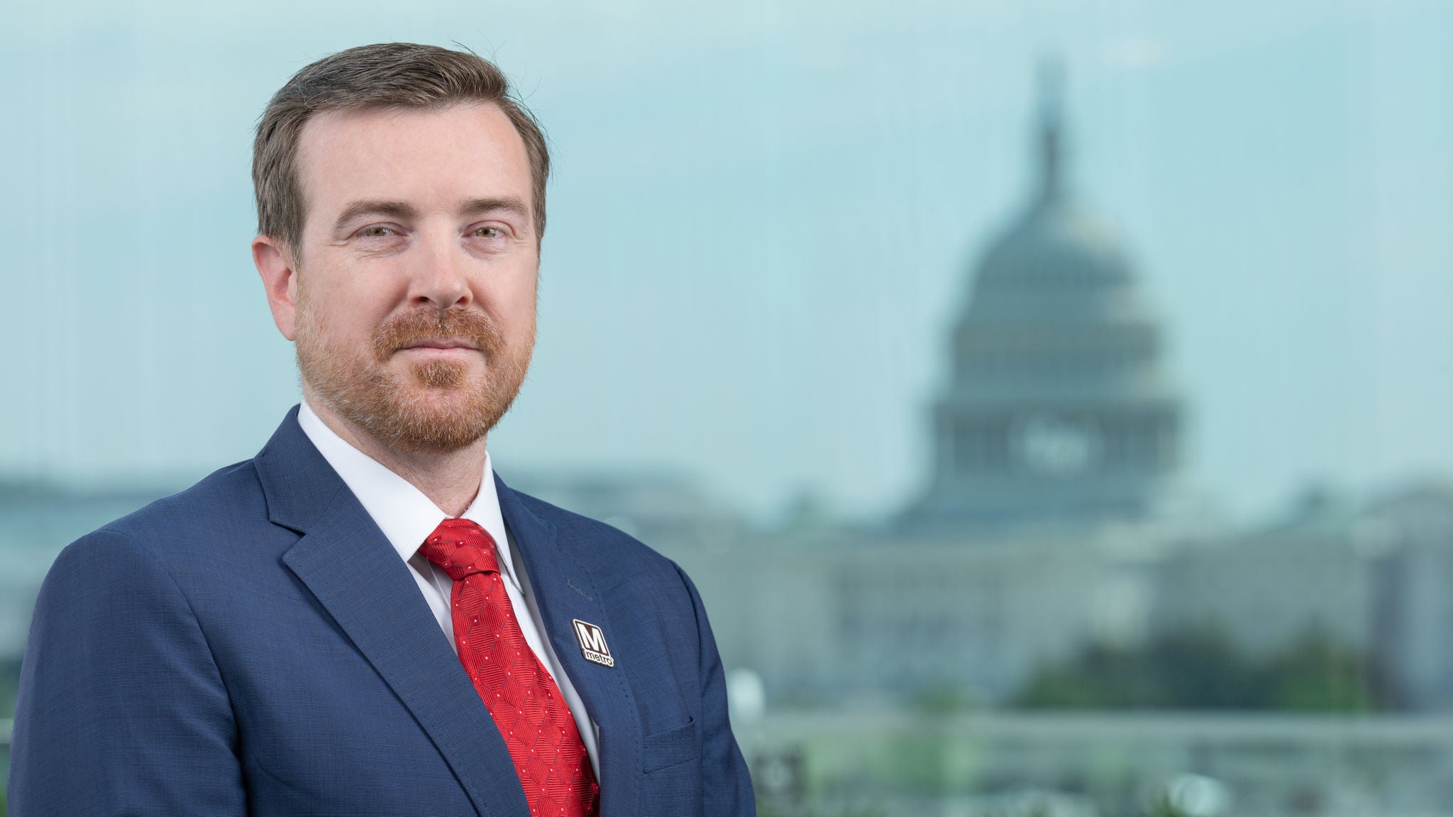 Headshot of Director Joe McAndrew wearing a blue suit and red tie.
