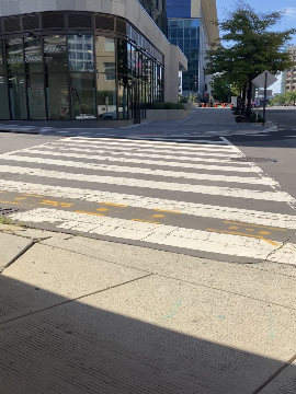 The picture shows a crosswalk across Virginia Avenue. After the crosswalk, there is a building to the left. 7th Street is also shown in the picture, to the right, as Virginia Avenue ends at the intersection.