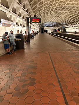 A picture of the Branch Avenue/Huntington Platform towards the end of the platform. The metro tracks are on the right and the wall and some benches are on the left.