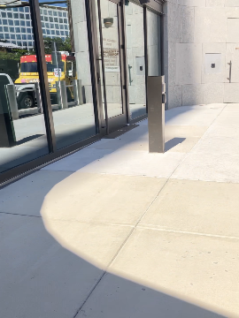A picture of the Transit Accessibility Center entrance and the Automatic Door Opener in front of it. The entrance to the building is on the left and the door opener is to the center-right of the frame.