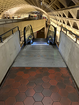 A picture of the escalator down to the Greenbelt side of the platform from the elevated mezzanine.